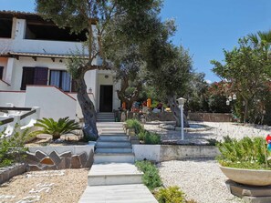 Stroll through the beautifully maintained garden, featuring a stone pathway and outdoor seating area with comfortable furniture.