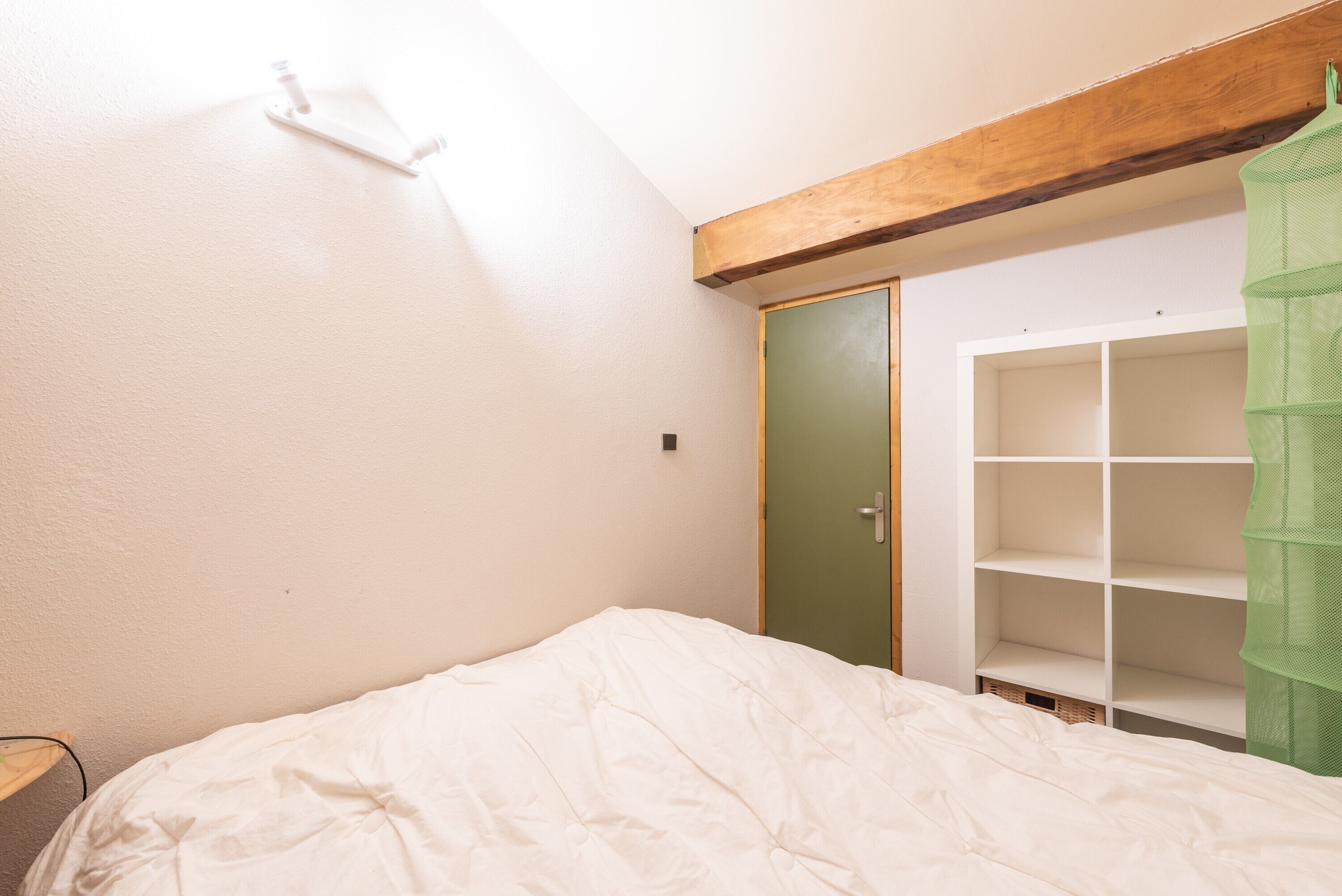Ein Schlafzimmer mit Bett, Kleiderschrank und einer grünen Hängematte.