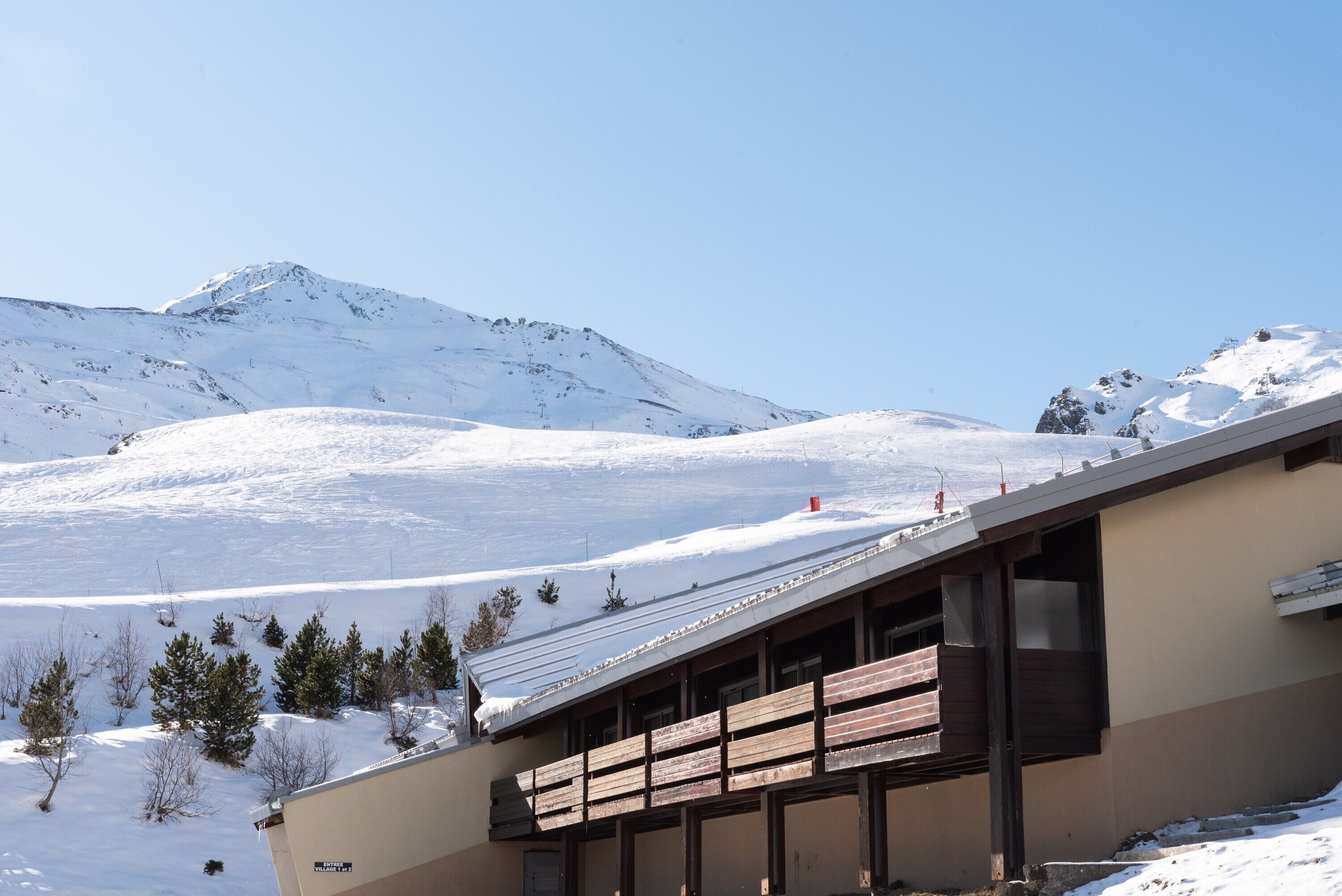 Un bâtiment doté d’un toit en pente, d’un balcon en bois et offrant une vue sur une montagne enneigée.