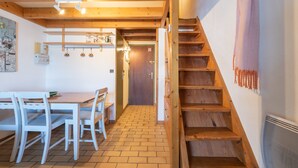 A wooden staircase, a dining area with a table and chairs, and a door leading to another room.