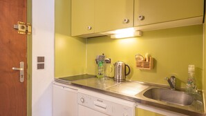 A compact kitchen with a dishwasher, a sink, and a coffee maker.