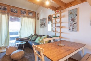 Un espacio de sala acogedor con una mesa de comedor de madera, un sofá y una ventana con cortinas.