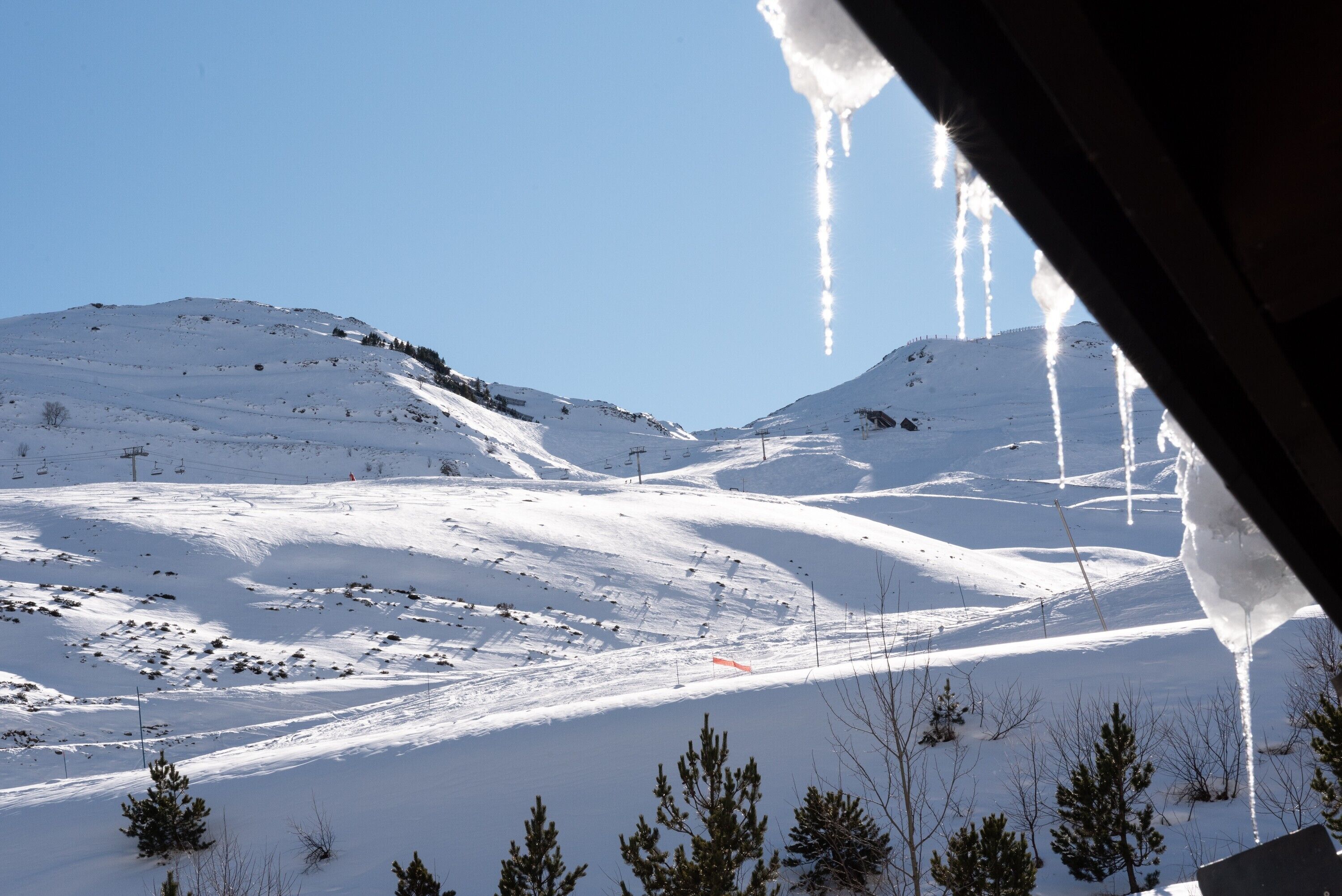 Paisaje nevado de montañas con pistas de esquí y cielo despejado.