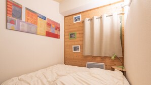 A bedroom with a bed, a wooden headboard, a wall-mounted artwork, and a window with a curtain.