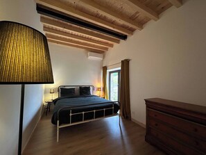 A bedroom with a bed, a lamp, a dresser, and a window with curtains. - Renovated barn in Dordogne - Swimming pool - 8-10 pers (Saint-Martial-de-Nabirat)