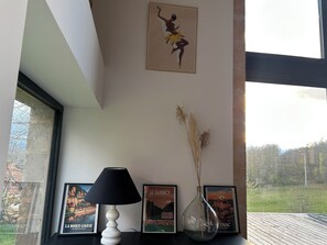 Et værelse med et vindue, en lampe og billeder i rammer på væggen.