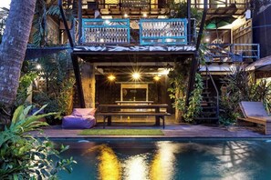 A modern building with a pool, outdoor seating, and a staircase leading to an upper level. - Singing River Front Villa (Tabanan)