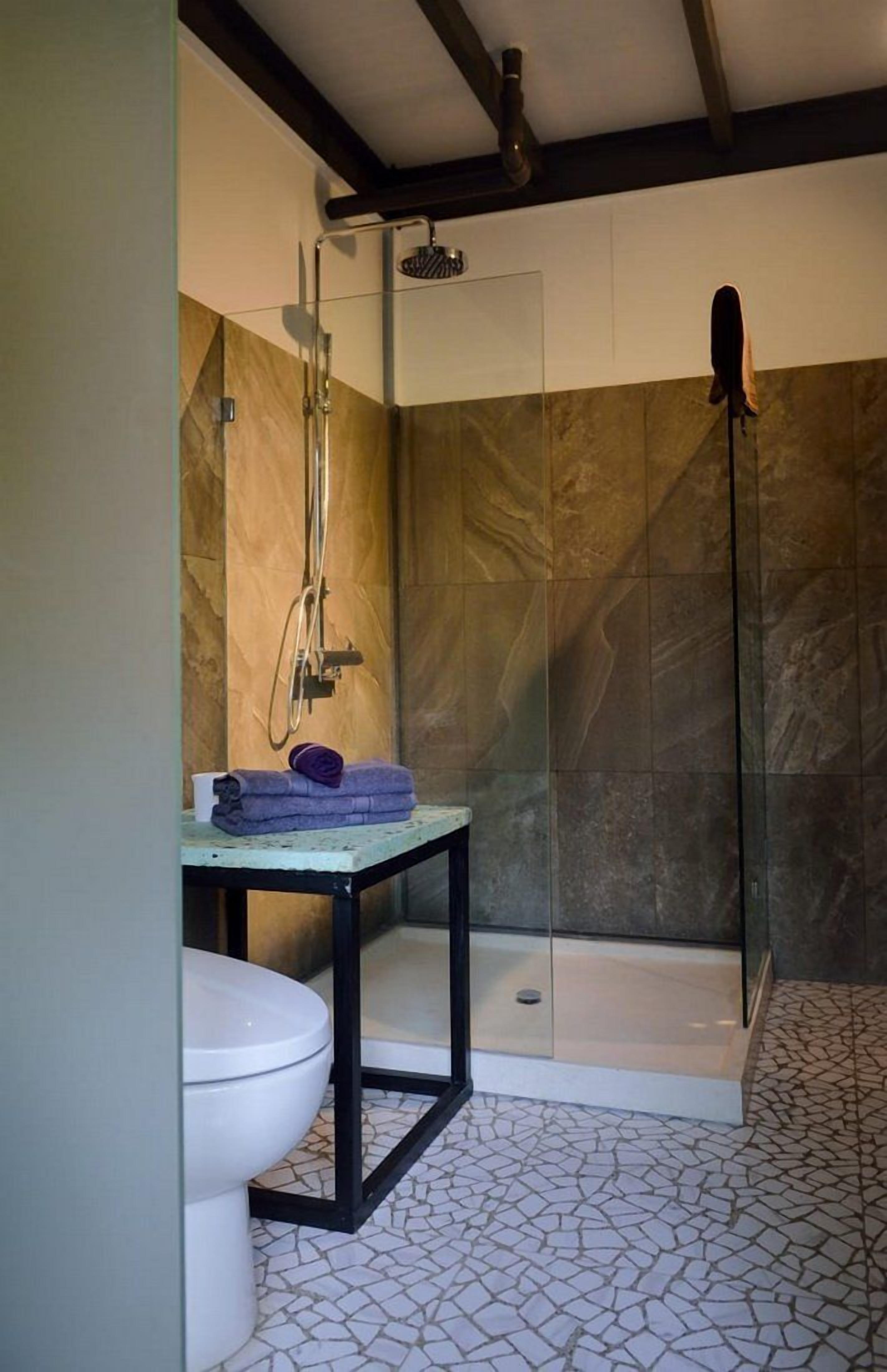 Un bagno moderno con doccia vetrata, un water e un lavabo con piano in marmo.