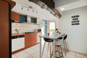 A kitchen with wooden cabinets, a dishwasher, a microwave, and a dining table with chairs.
