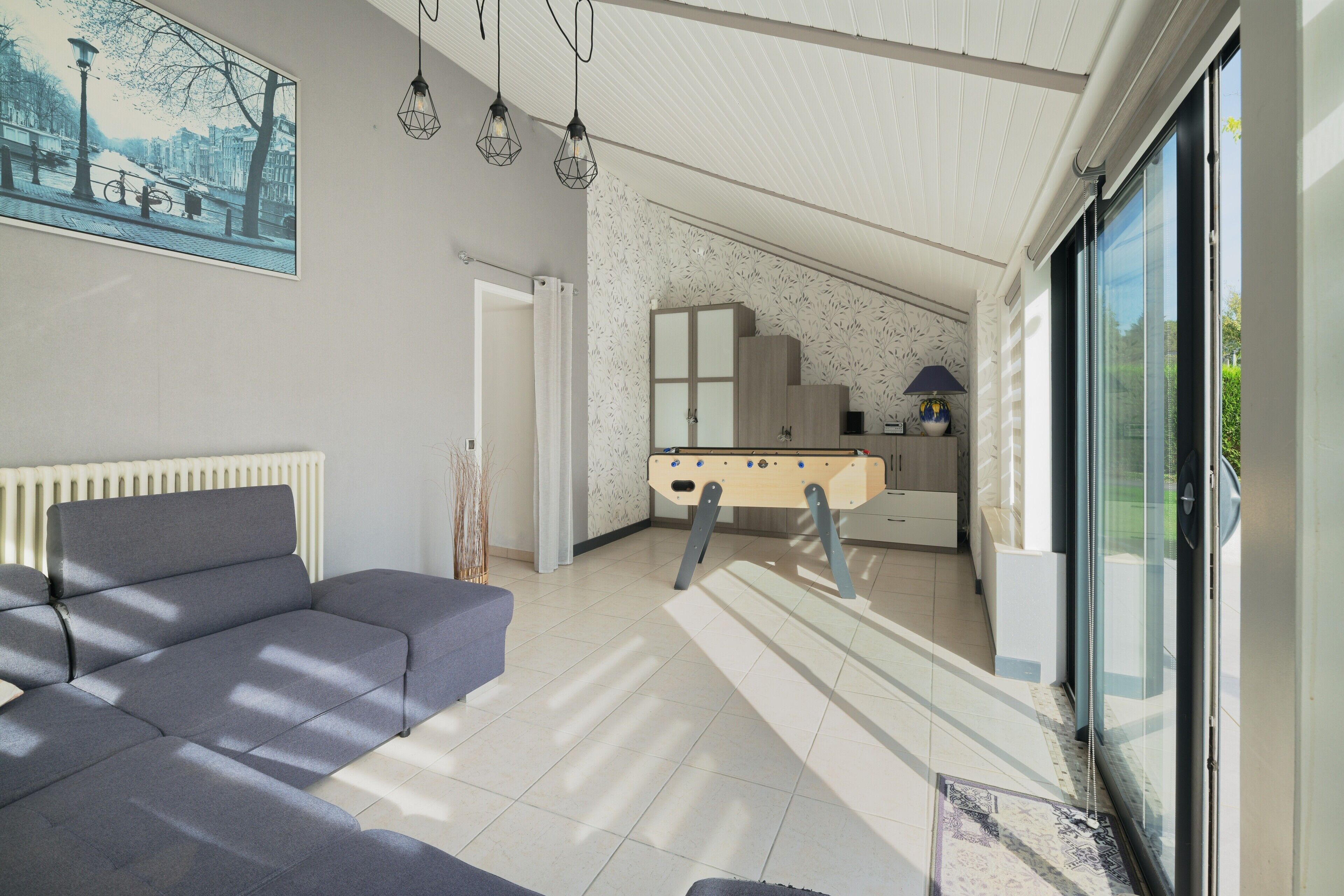Een moderne woonkamer met een bank, een tafelvoetbalspel en een groot raam.