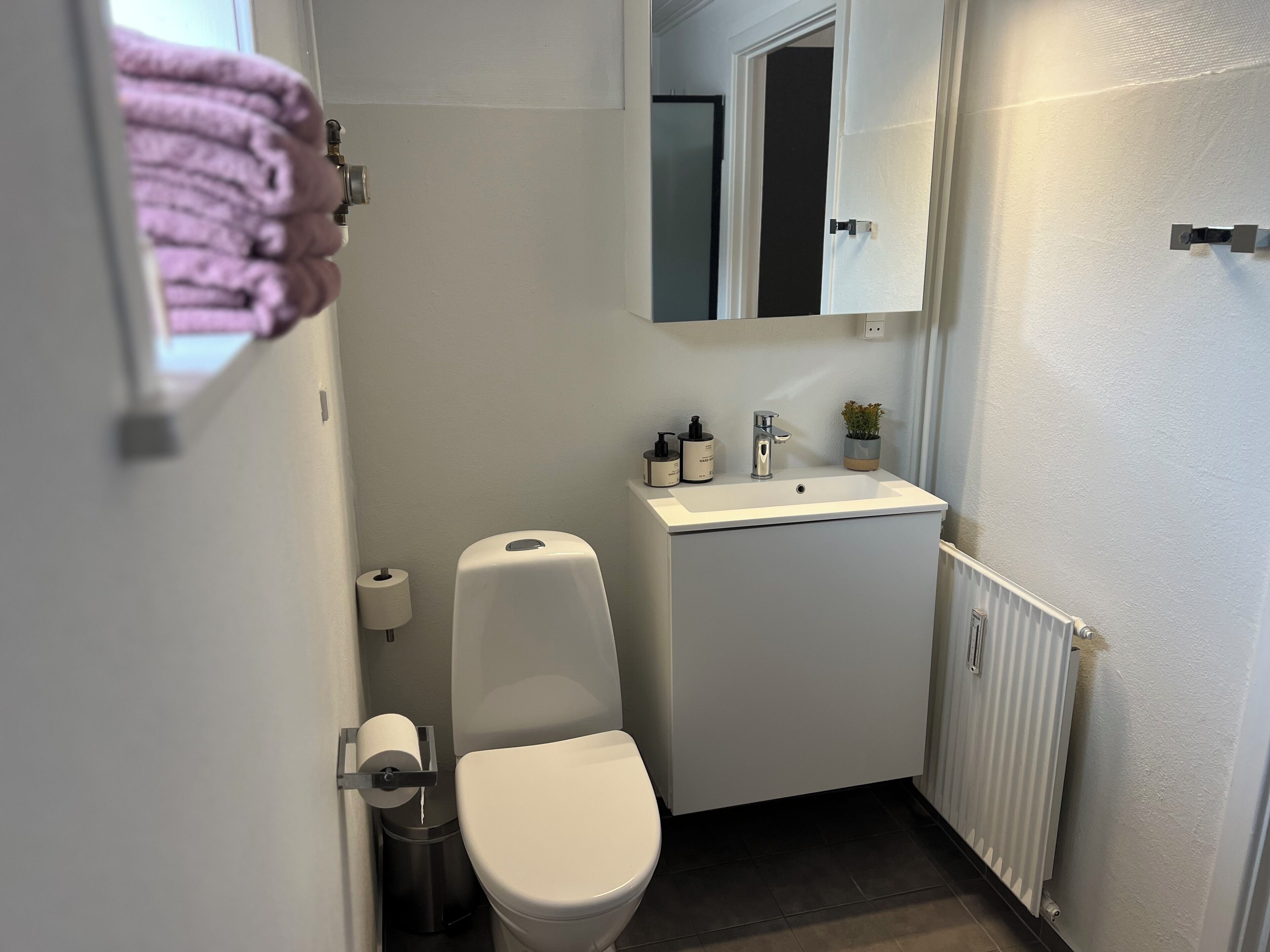 A compact bathroom with a toilet, sink, and mirror.