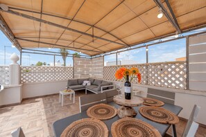 An outdoor patio with a covered seating area, a table with woven placemats, and a bottle of wine. - Apartment 'Stonehouse Oasis' with Private Terrace, Wi-Fi and Air Conditioning (Sant'Isidoro)