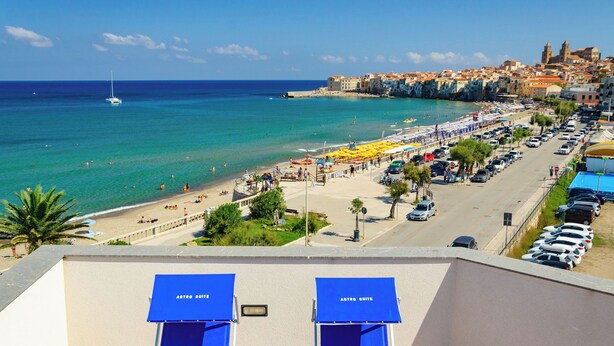 A coastal hotel with a beach view, a parking area, and a street with cars. - Astro Suite (Cefalù)