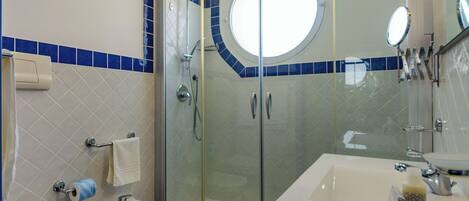 Un bagno con doccia vetrata, lavandino bianco, WC e bidet.