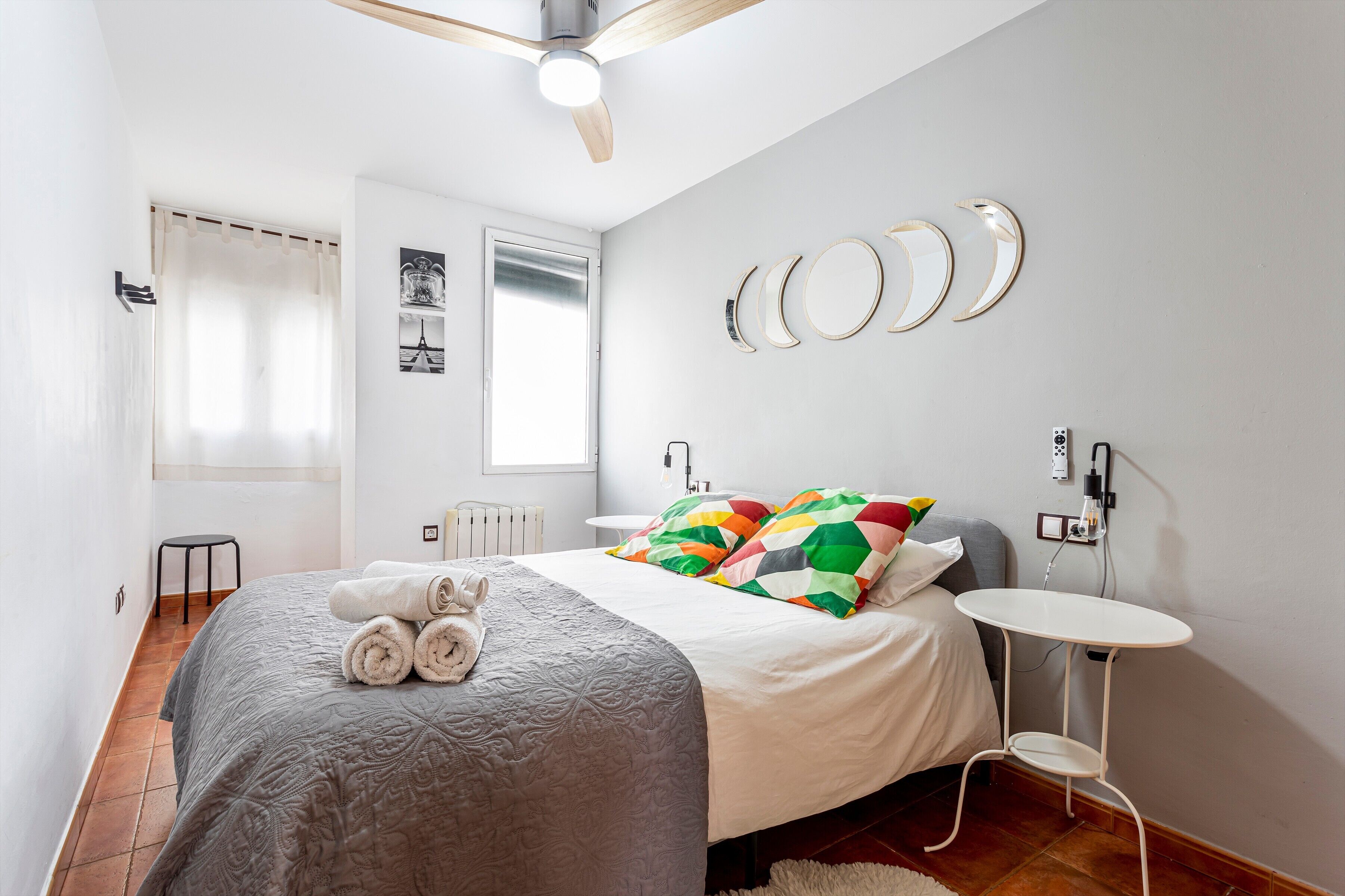 Een slaapkamer met een bed, een plafondventilator, een tafeltje en een radiator.