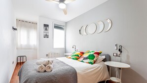 A bedroom with a bed, a ceiling fan, a small table, and a radiator. - Apartment 'Torres De Quart Tu Casa' with Balcony, Wi-Fi and Air Conditioning (València)