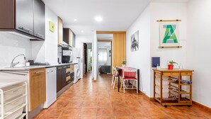 A modern kitchen with a dishwasher, oven, and cabinets. There is a dining area with a table and chairs. - Apartment 'Torres De Quart Tu Casa' with Balcony, Wi-Fi and Air Conditioning (València)