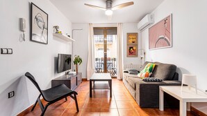 A modern living room with a sofa, a TV, a dining table, and a ceiling fan. - Apartment 'Torres De Quart Tu Casa' with Balcony, Wi-Fi and Air Conditioning (València)