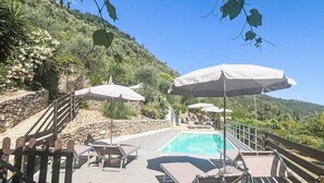 A poolside area with lounge chairs, umbrellas, and a wooden deck.