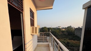 Ένα μπαλκόνι με θέα στην πόλη, ένα παράθυρο με κάγκελα και μια πόρτα που οδηγεί σε έναν εσωτερικό χώρο.