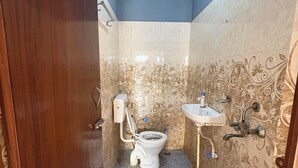 Ένα μικρό μπάνιο με τουαλέτα, νιπτήρα και έναν κουβά.