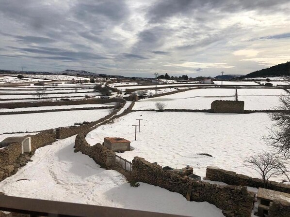 A rural landscape with snow-covered fields and stone walls.