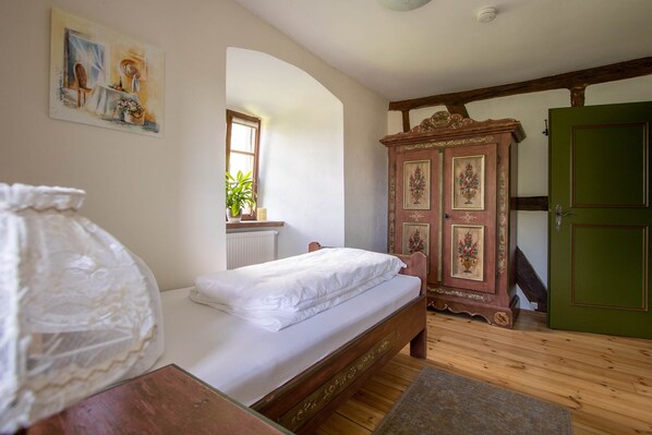 Un dormitorio con una cama de madera, una puerta verde y una ventana con una planta.