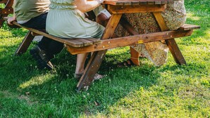 Un grupo de personas sentadas en una mesa de picnic de madera bajo un paraguas grande.