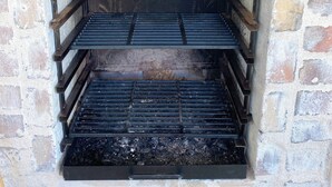 A stone fireplace with a metal grate and a wooden ladder. - Absolute peace and terrace in Bastille (Paris)