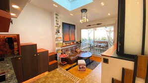 A modern interior with a skylight, a dining area, a sofa, and a kitchen area. - Absolute peace and terrace in Bastille (Paris)