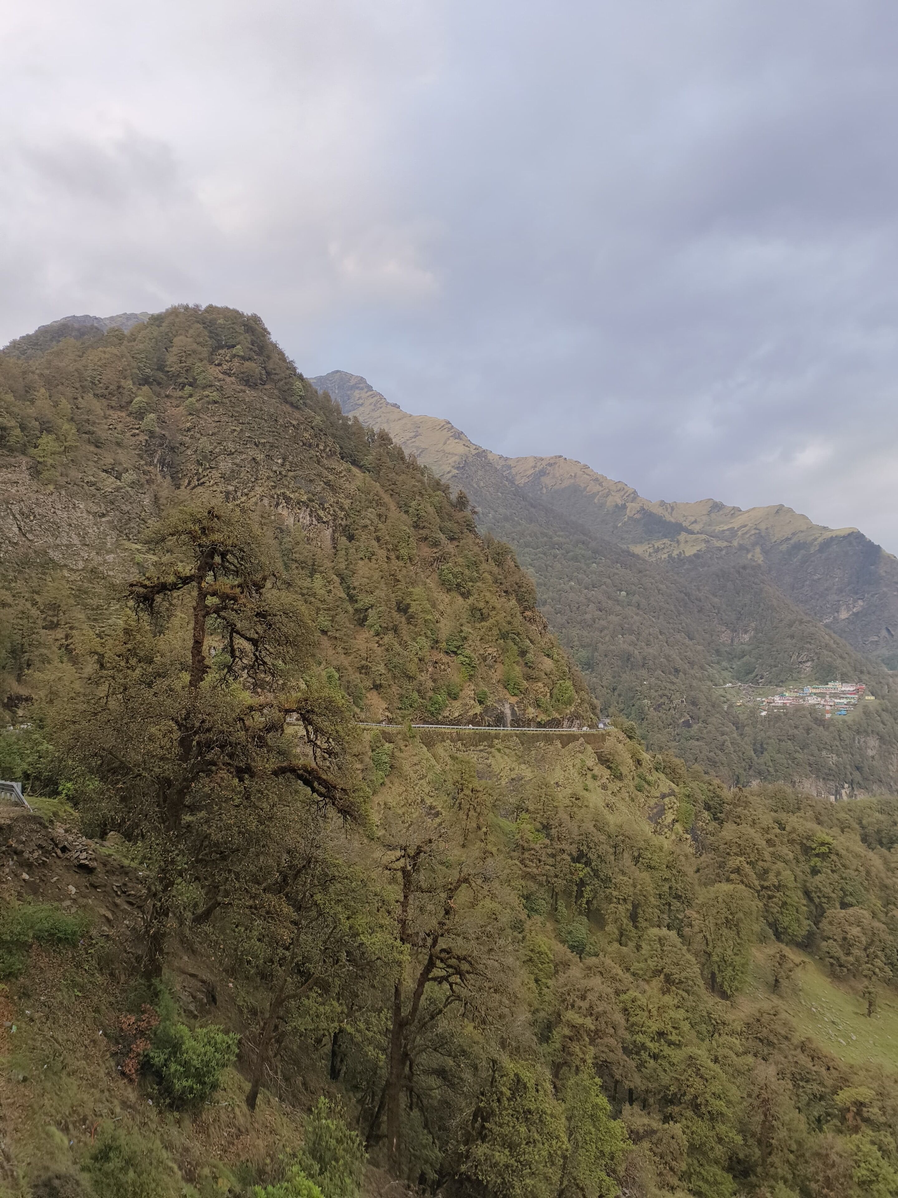 A mountainous landscape with a bridge and a settlement in the valley.