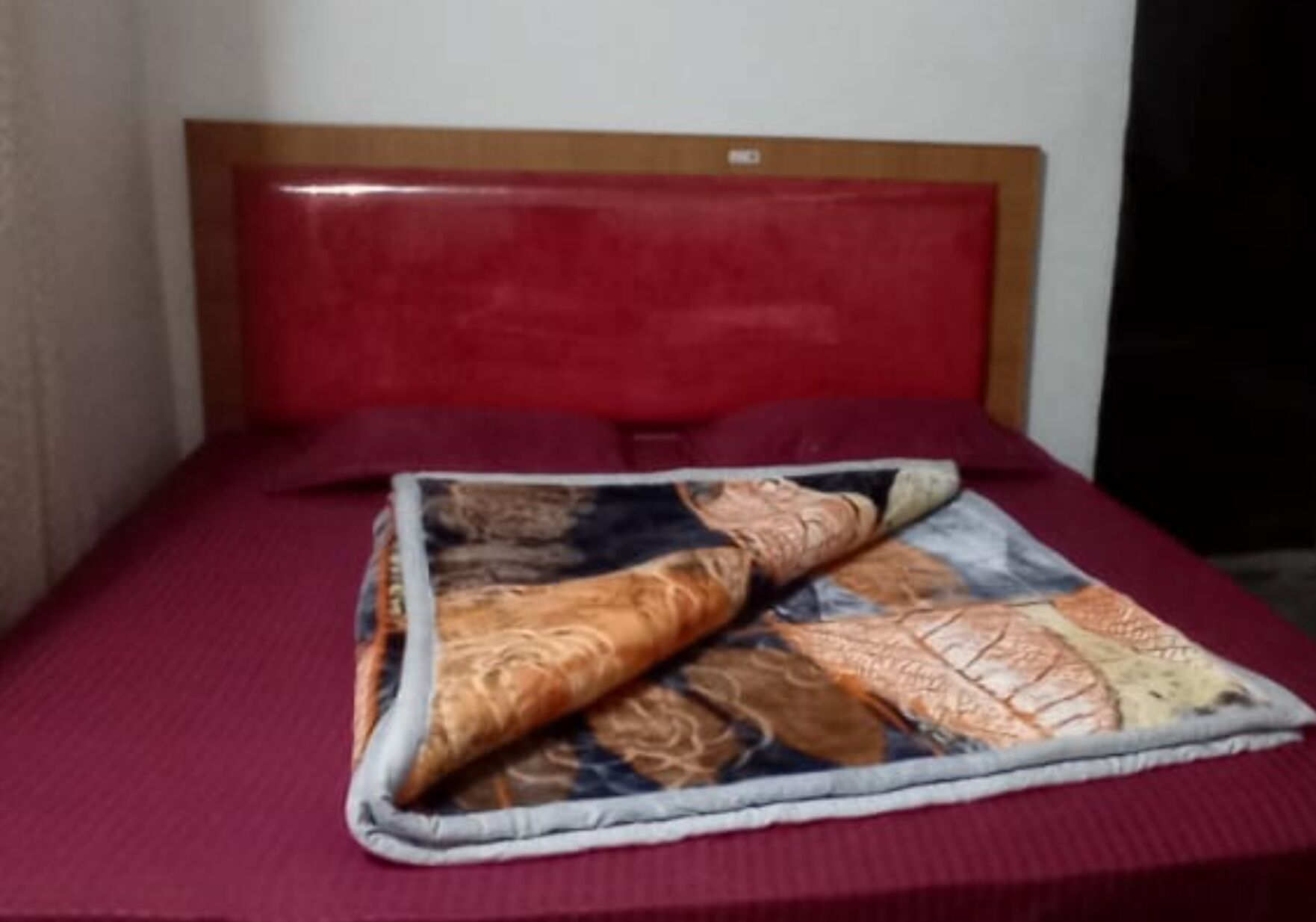 A bed with a red headboard and a patterned blanket.