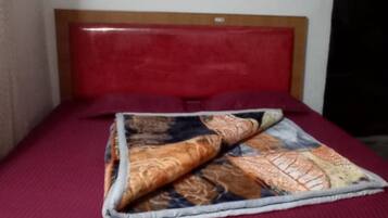 A bed with a red headboard and a patterned blanket.