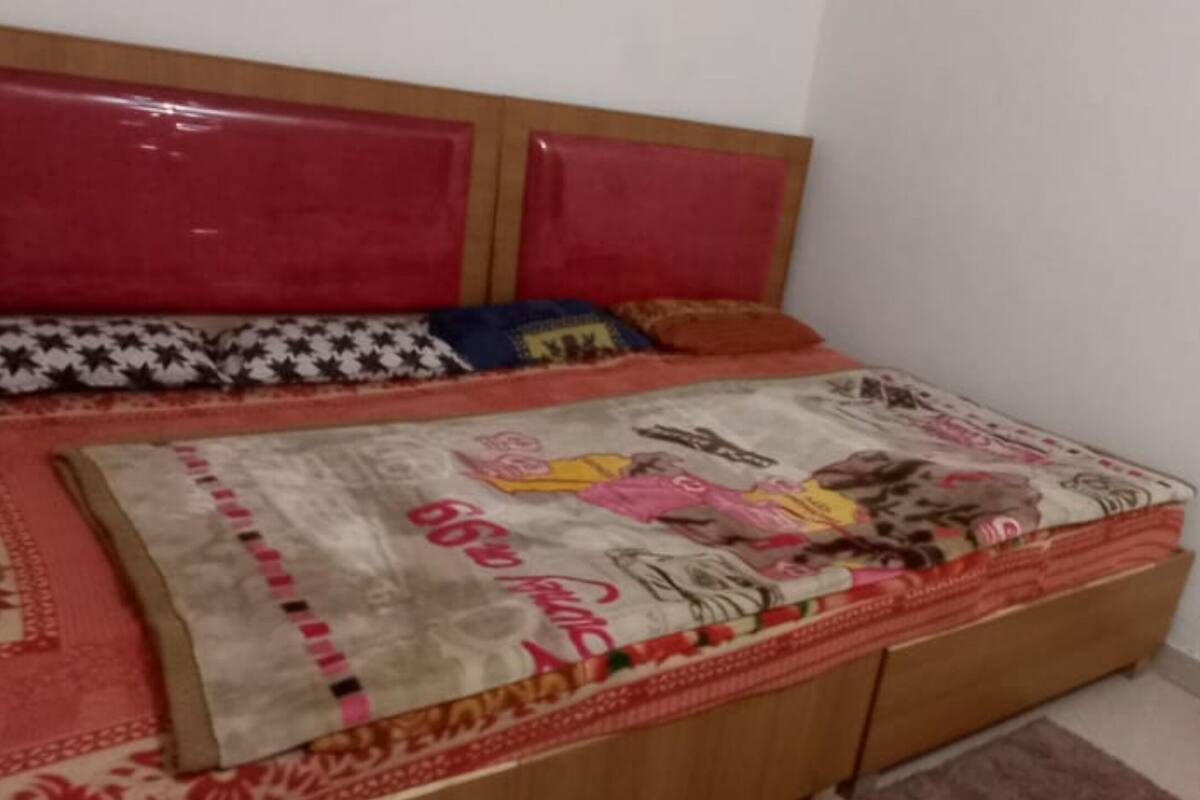 Ein Bett mit einem gemusterten Überwurf, einem Kopfteil und einem hölzernen Kopfstück.