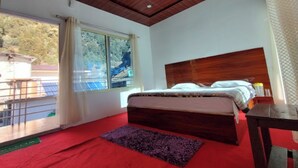 Une chambre à coucher avec une tête de lit en bois, un lit recouvert de draps blancs, un tapis violet et une fenêtre avec des rideaux.