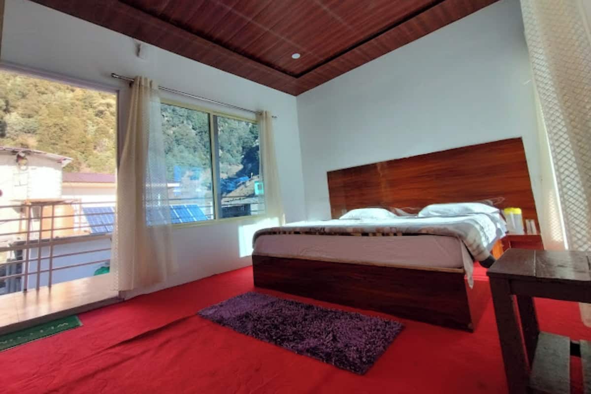 Ein Schlafzimmer mit einem hölzernen Kopfende, einem Bett mit weißen Bettwäsche, einem violetten Teppich und einem Fenster mit Vorhängen.