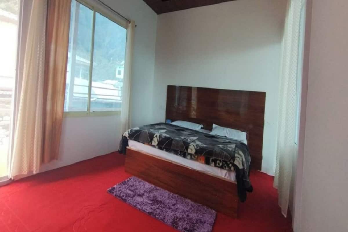Ein Schlafzimmer mit großem Fenster, Holz-Kopfteil und rotem Teppich.