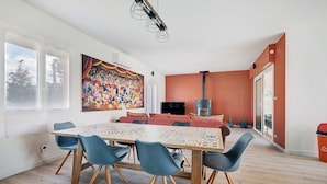 Un espace repas avec une grande table, des chaises bleues et une fresque colorée sur le mur.