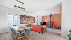 Un salon moderne comprenant une table à manger, des chaises, un canapé, un téléviseur et une cheminée.
