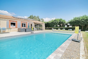 Una piscina con borde de baldosas, un edificio con ventanas y una puerta, y un letrero con el número 8.