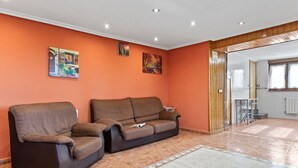Un salon avec deux canapés, un sol carrelé et une porte en bois donnant sur une autre pièce.