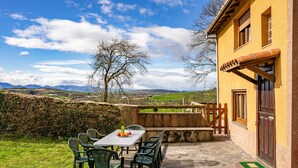 Une terrasse avec une table et des chaises, un sol en pierre et une vue sur la campagne.