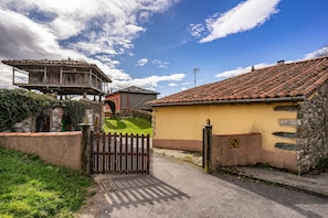 Propiedad rural con entrada porticada, muro de piedra y edificio con techo de tejas.