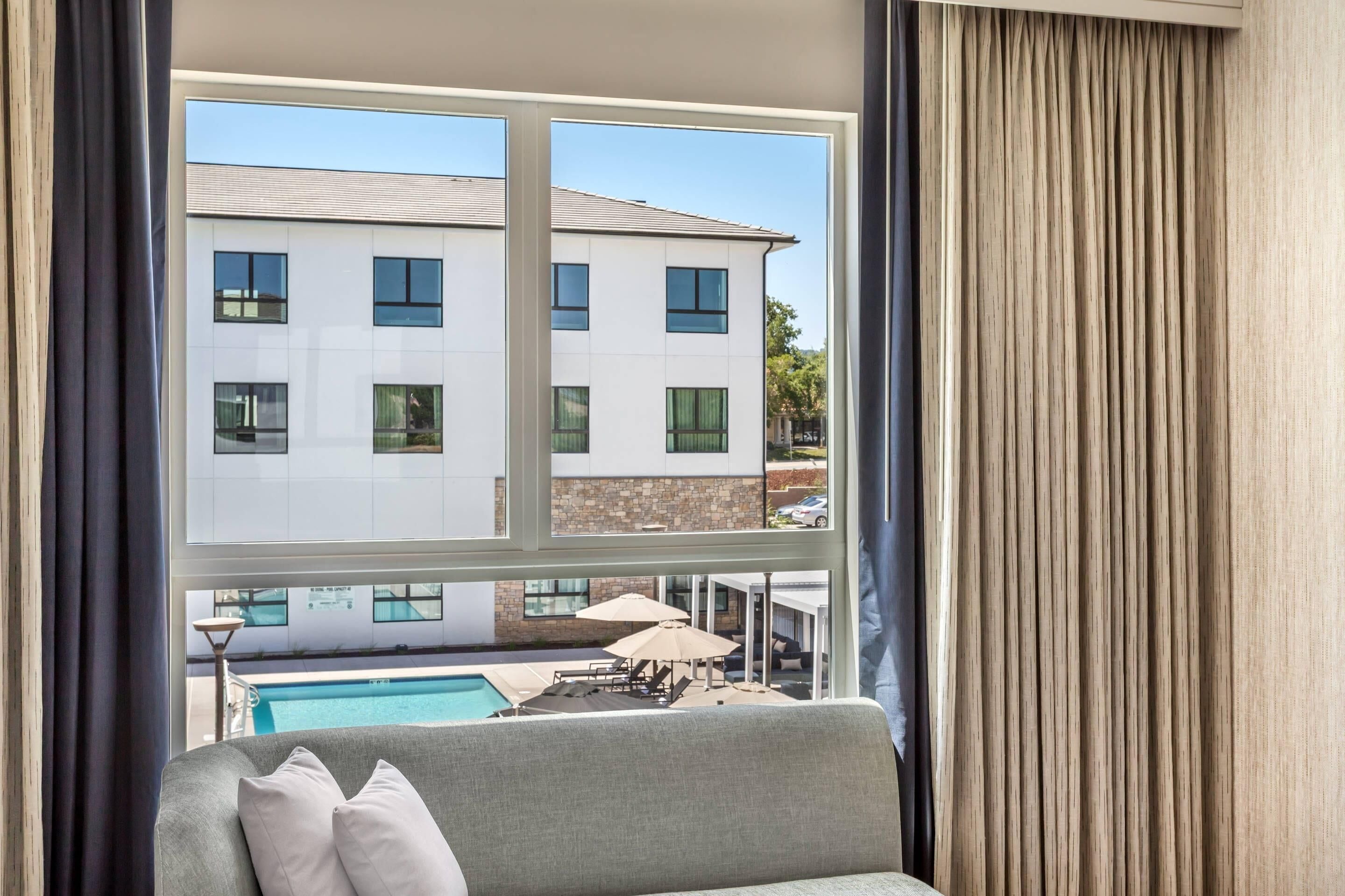 Quarto com vista para um edifício, uma piscina e mobiliário de exterior.
