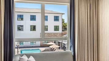 Quarto com vista para um edifício, uma piscina e mobiliário de exterior.