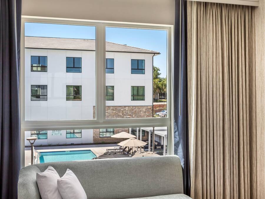 Quarto com vista para um edifício, uma piscina e mobiliário de exterior.