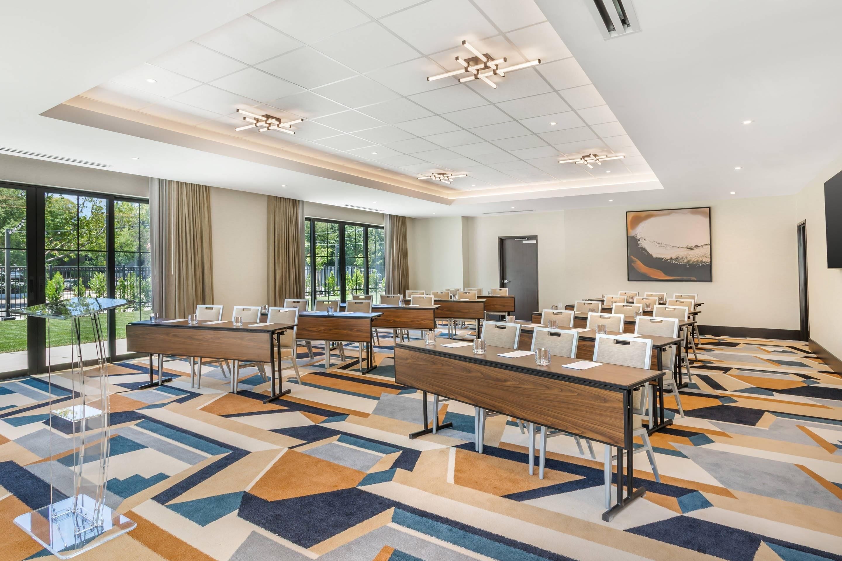 A conference room with a long table, chairs, and a patterned carpet.