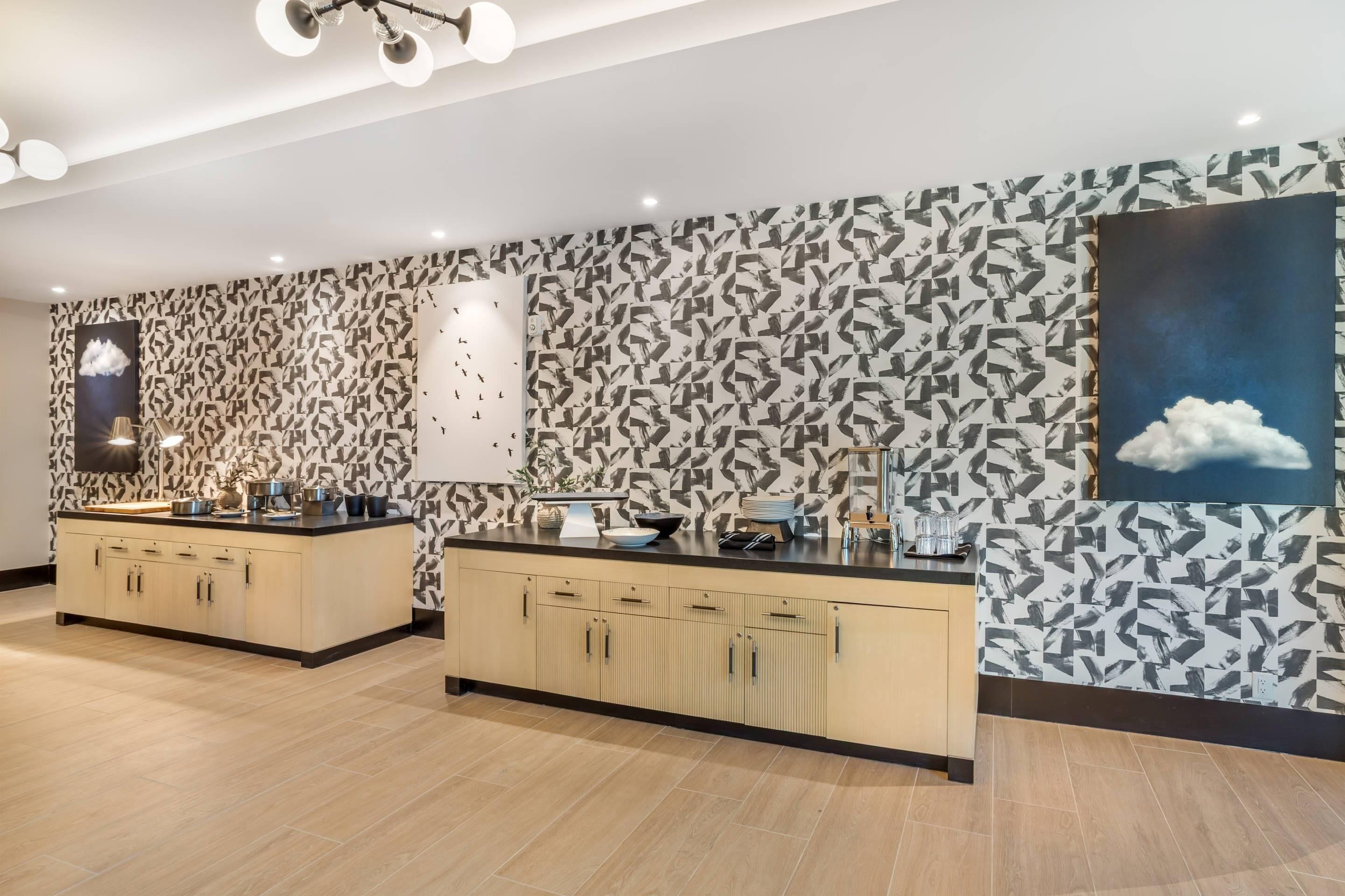 Una cocina moderna con dos islas, un papel tapiz estampado y un lámpara colgante.