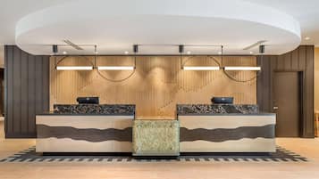 A reception desk with two counters, a modern light fixture, and a patterned floor.
