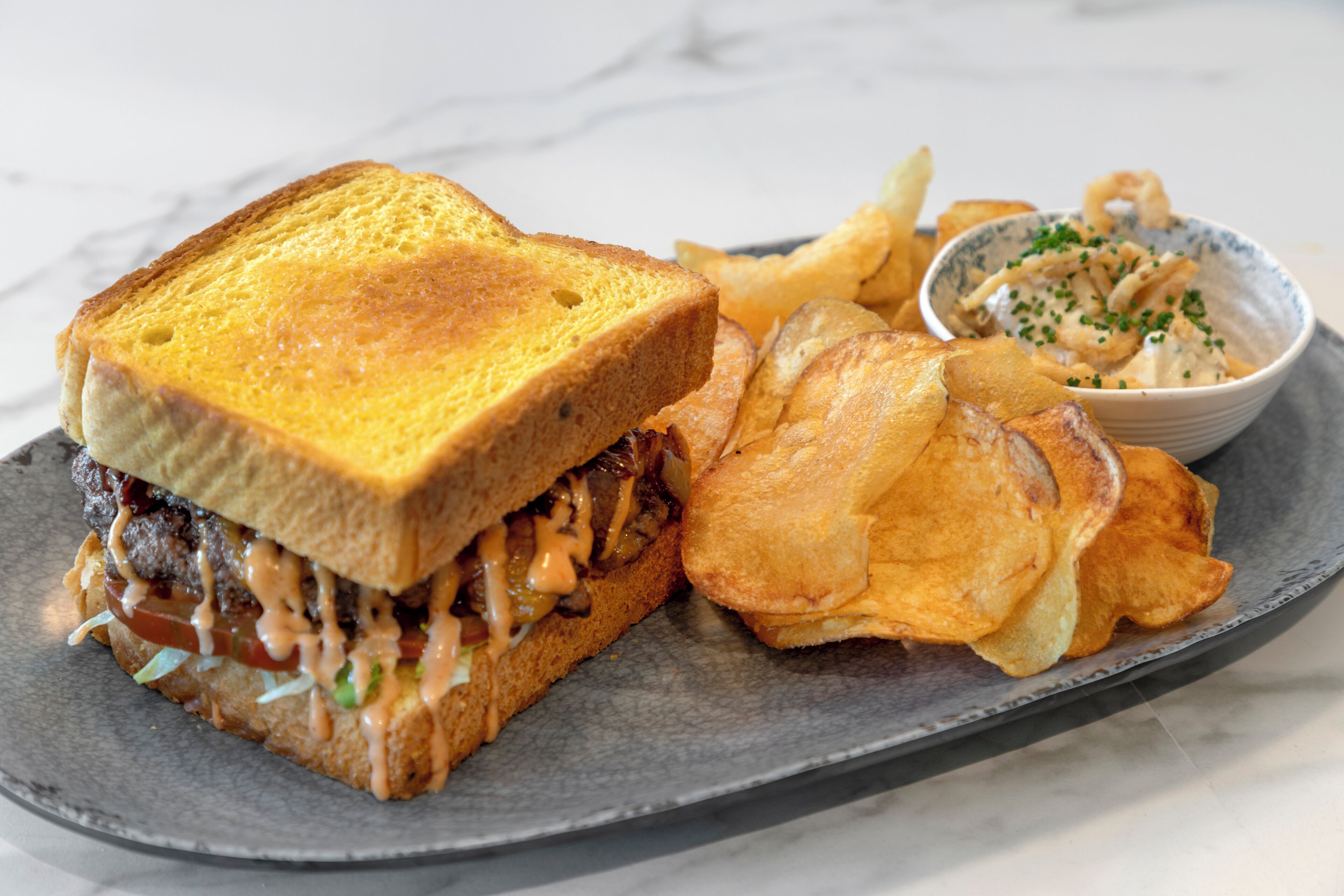 Un sandwich accompagné de frites et d’une petite portion de sauce, le tout servi sur une assiette.
